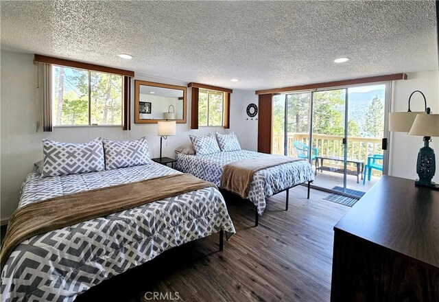 bedroom with access to exterior, hardwood / wood-style floors, multiple windows, and a textured ceiling