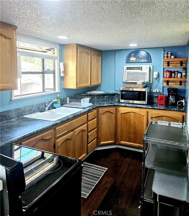 kitchen with electric range, sink, a wall mounted air conditioner, a textured ceiling, and dark hardwood / wood-style flooring