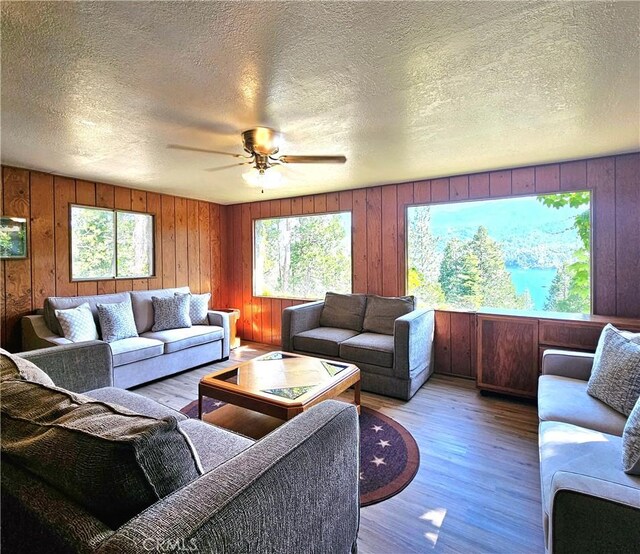 living room featuring a textured ceiling, ceiling fan, and light hardwood / wood-style floors