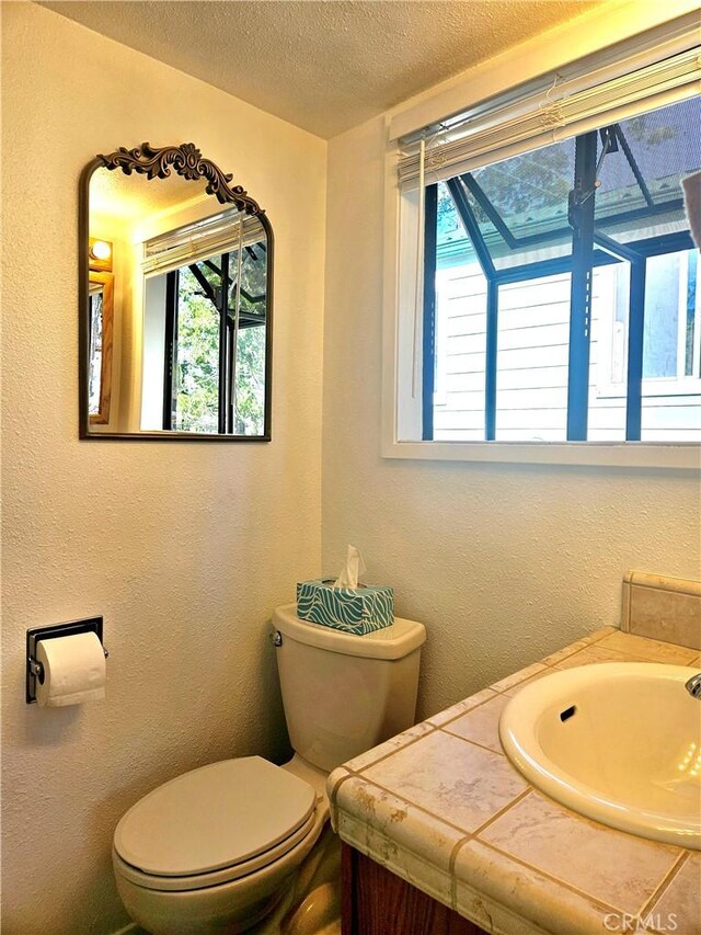 bathroom with toilet, a textured ceiling, and vanity