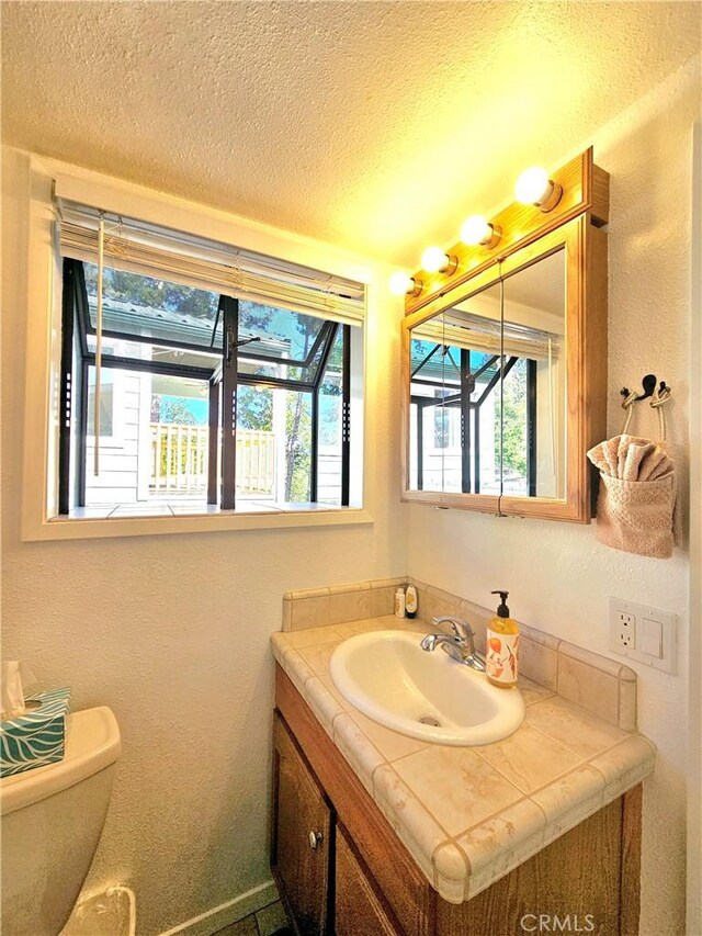 bathroom featuring a textured ceiling, toilet, and vanity