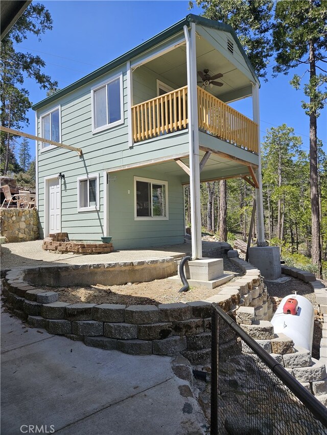 rear view of property featuring a balcony and ceiling fan