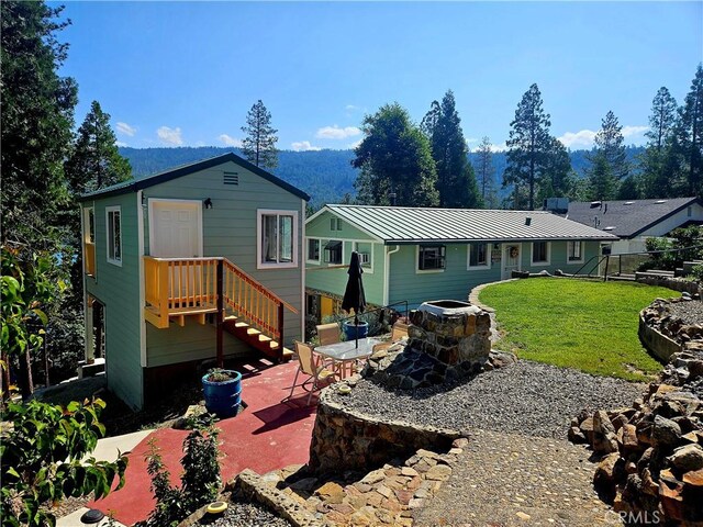 back of house featuring a fire pit, a lawn, and a patio