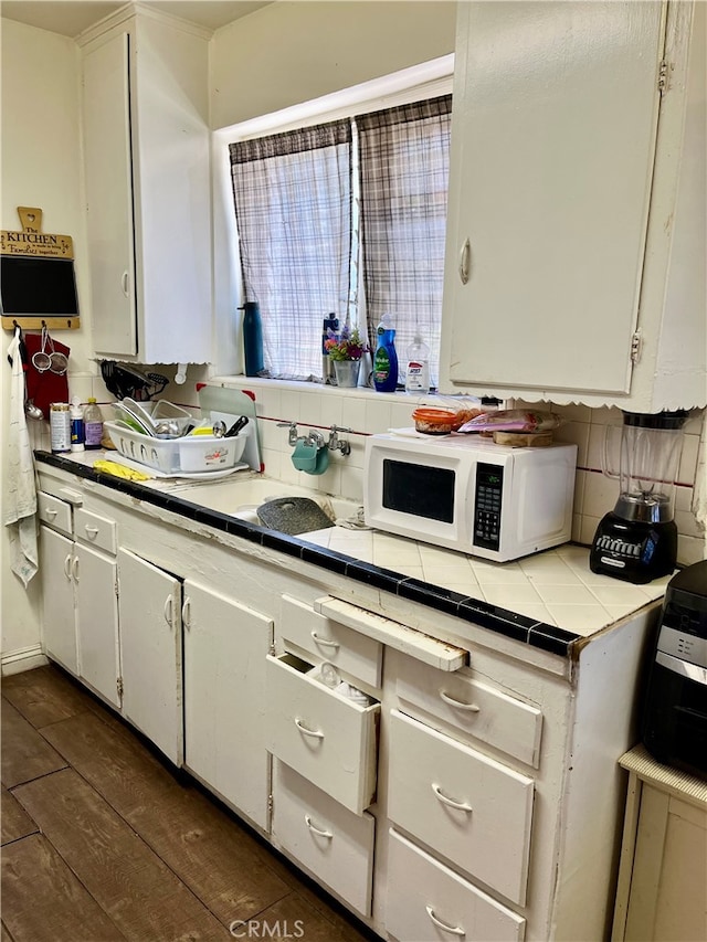 kitchen with dark wood-type flooring, white cabinetry, tile counters, and tasteful backsplash