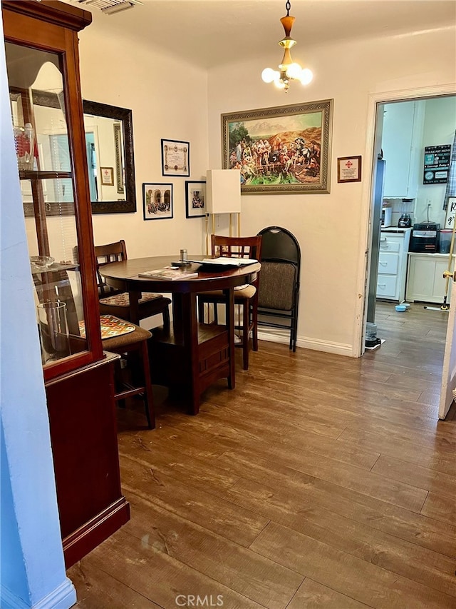 dining area with dark hardwood / wood-style floors and an inviting chandelier