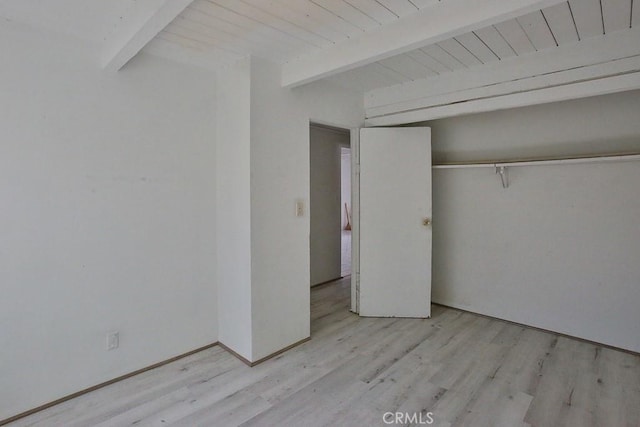 unfurnished bedroom with a closet, beamed ceiling, and light wood-type flooring