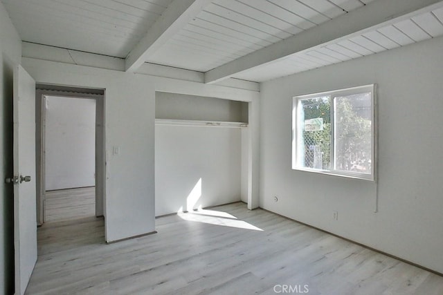 unfurnished bedroom featuring a closet, beamed ceiling, and light hardwood / wood-style floors