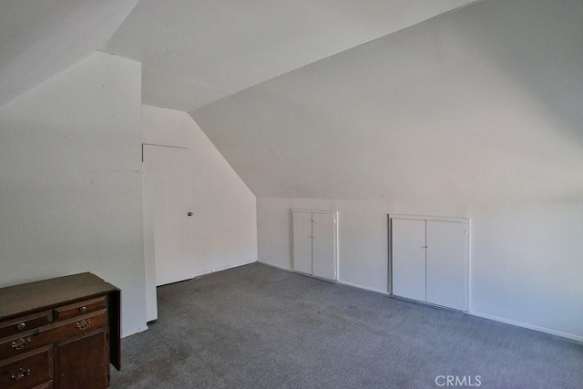 additional living space featuring dark carpet and lofted ceiling