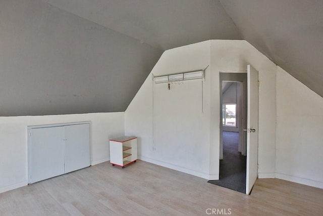 additional living space featuring light wood-type flooring and lofted ceiling