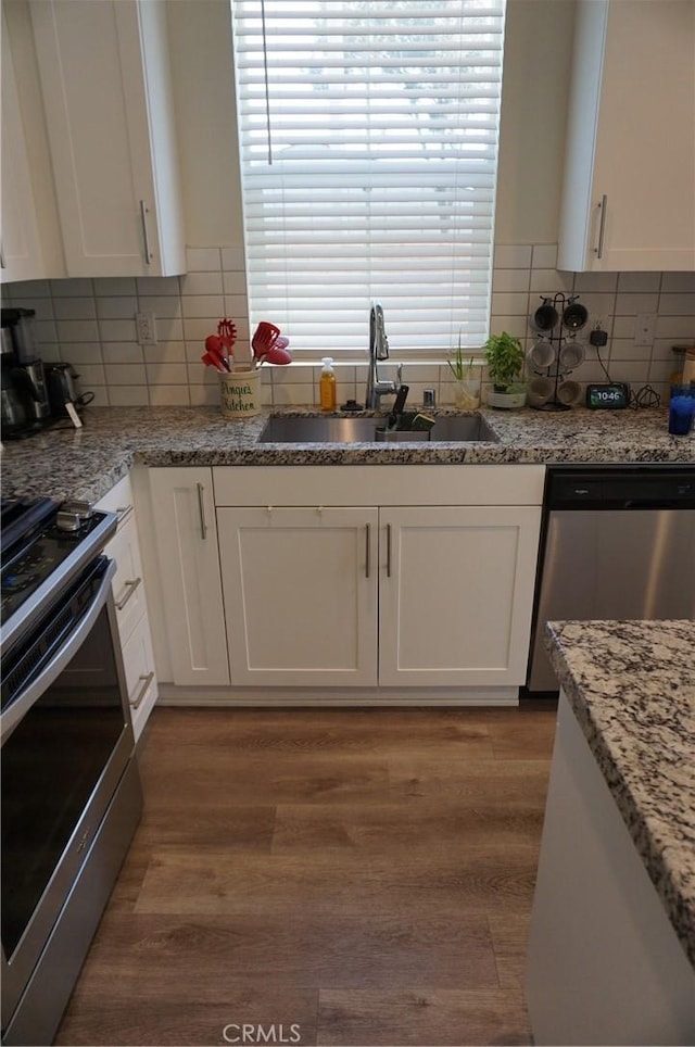 kitchen with dark hardwood / wood-style flooring, white cabinetry, sink, and appliances with stainless steel finishes