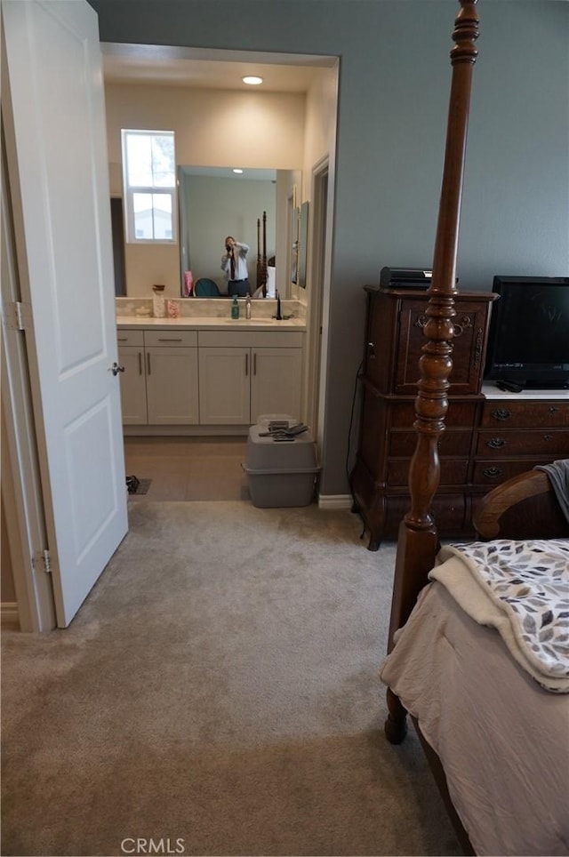 bedroom featuring ensuite bathroom, light colored carpet, and sink