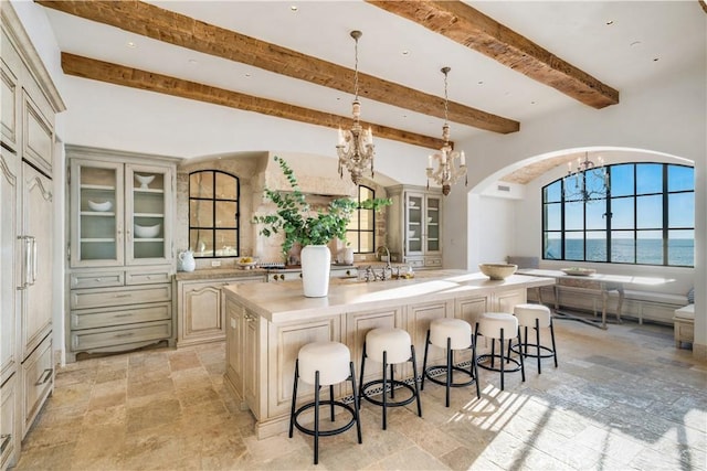 kitchen featuring a notable chandelier, a spacious island, a water view, and cream cabinets