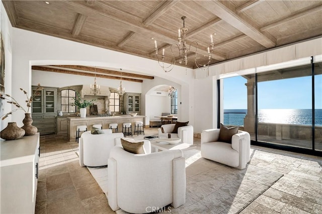 living room featuring beam ceiling, a water view, a notable chandelier, and wood ceiling