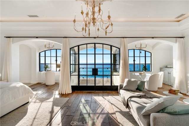 bedroom featuring hardwood / wood-style floors, a water view, and an inviting chandelier