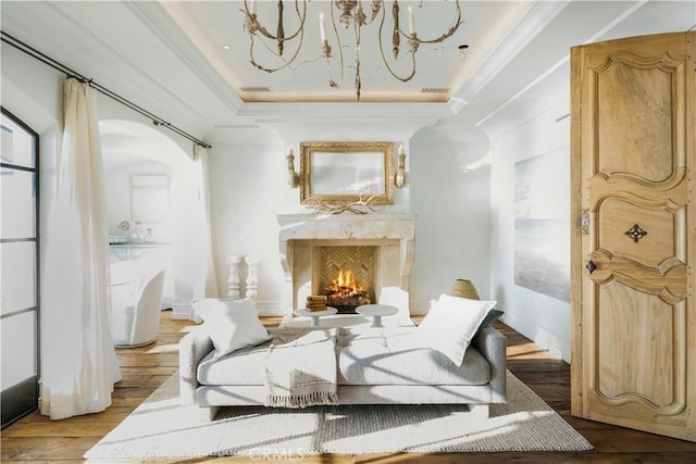 sitting room with a premium fireplace, ornamental molding, a tray ceiling, and light hardwood / wood-style flooring