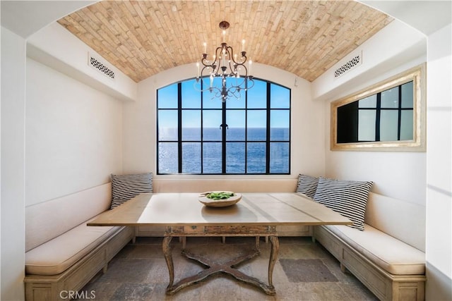 dining area with breakfast area, a water view, vaulted ceiling, and brick ceiling