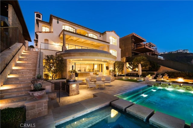 rear view of house featuring a patio area, a balcony, an outdoor hangout area, and a swimming pool with hot tub