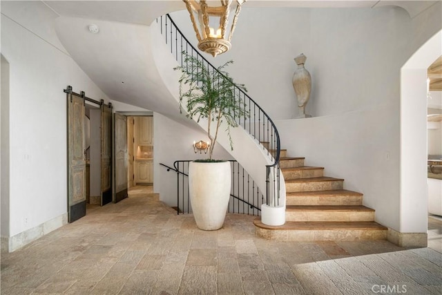 stairway with a barn door and lofted ceiling