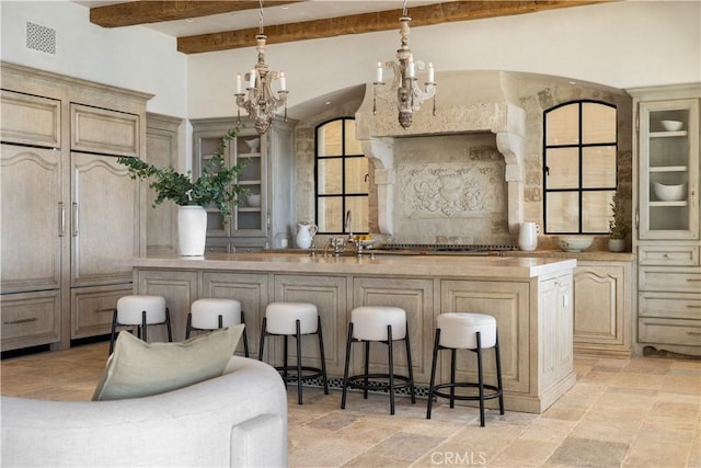 kitchen featuring pendant lighting, a breakfast bar, a center island with sink, sink, and cream cabinetry