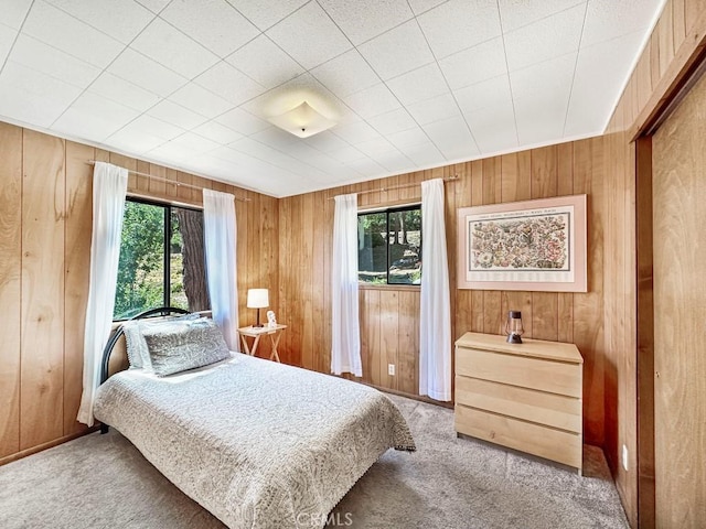 carpeted bedroom with multiple windows and wood walls