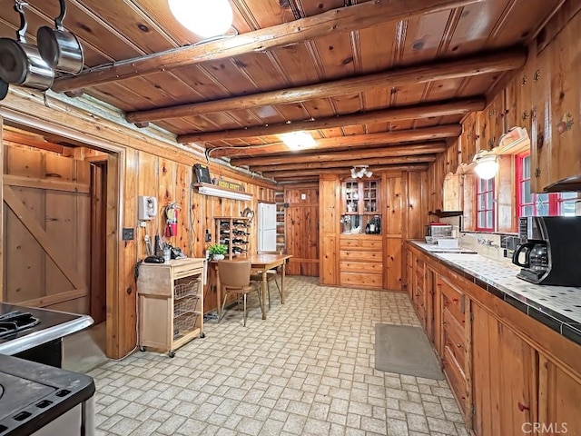 kitchen featuring beam ceiling, tile counters, wooden ceiling, hanging light fixtures, and wood walls