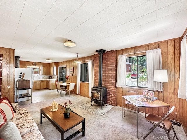 living room with a wood stove, wooden walls, and light colored carpet