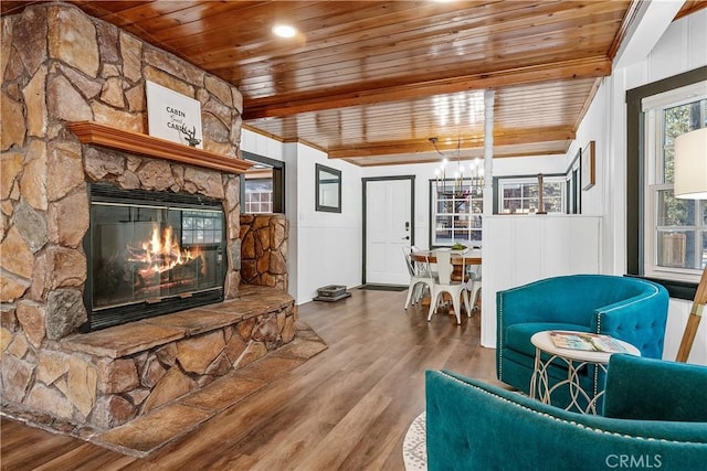 living room featuring hardwood / wood-style flooring, a stone fireplace, beam ceiling, and wooden ceiling