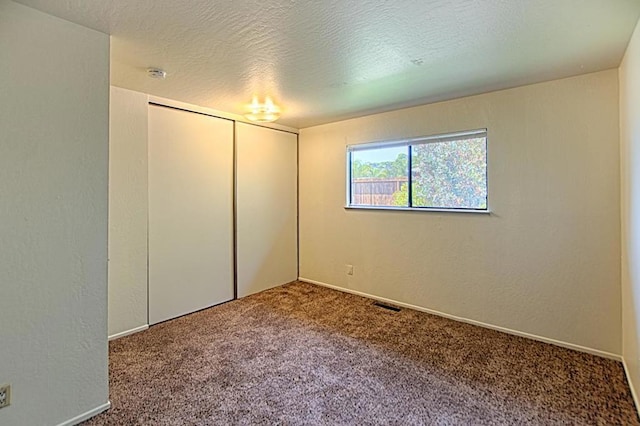 unfurnished bedroom featuring a closet, carpet floors, and a textured ceiling