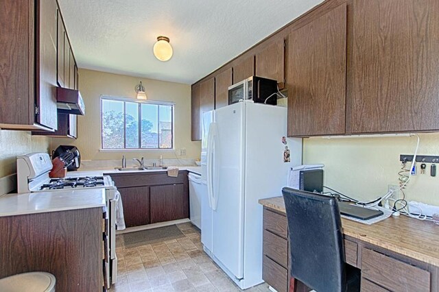 kitchen featuring light tile floors, white appliances, dark brown cabinets, and sink