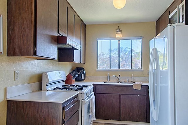 kitchen featuring white appliances, sink, and dark brown cabinets