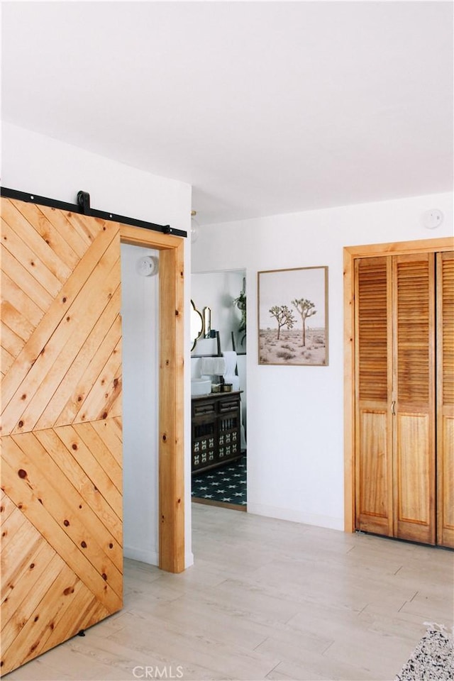 corridor featuring a barn door and light wood-type flooring