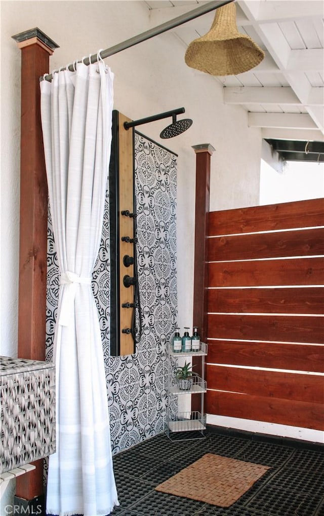 bathroom featuring beamed ceiling and curtained shower