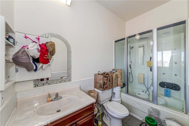 full bathroom featuring tile floors, enclosed tub / shower combo, toilet, and vanity