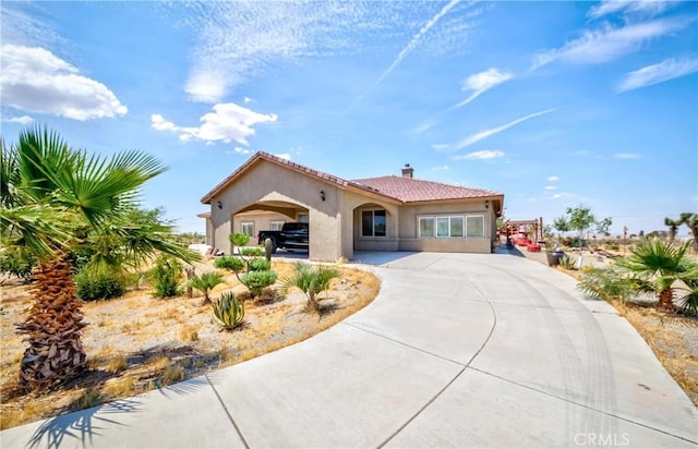 mediterranean / spanish-style home featuring a tile roof, a chimney, concrete driveway, and stucco siding