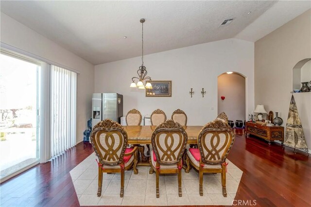 dining space featuring a notable chandelier, lofted ceiling, and light hardwood / wood-style flooring