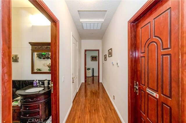 hallway with tile walls, light hardwood / wood-style floors, and sink