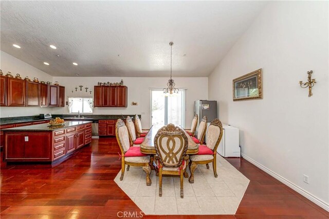 dining room featuring dark wood-type flooring, sink, a chandelier, and lofted ceiling