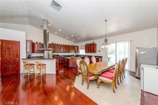 dining area featuring a notable chandelier, lofted ceiling, and dark wood-type flooring