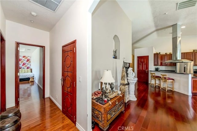 interior space featuring arched walkways, visible vents, baseboards, and wood finished floors