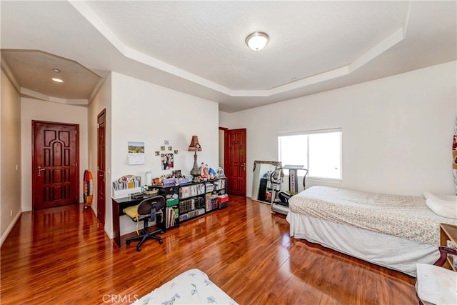 bedroom featuring a raised ceiling and dark hardwood / wood-style floors