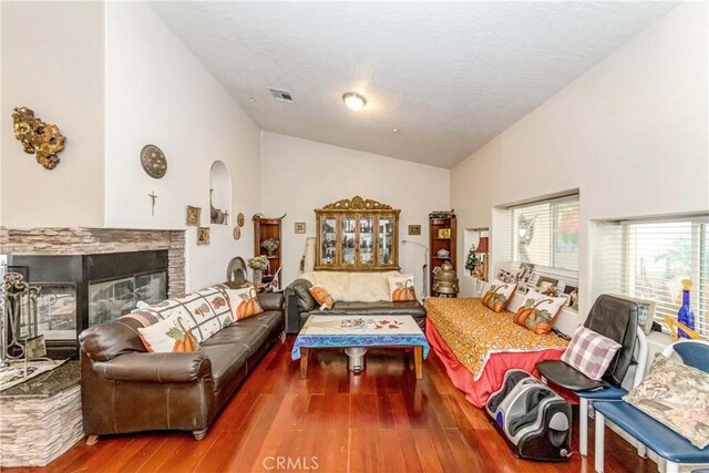 living room featuring a stone fireplace, dark hardwood / wood-style floors, and high vaulted ceiling