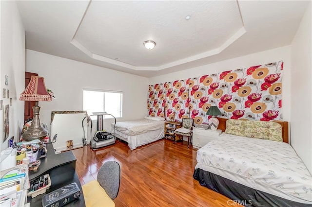 bedroom with a raised ceiling and hardwood / wood-style flooring