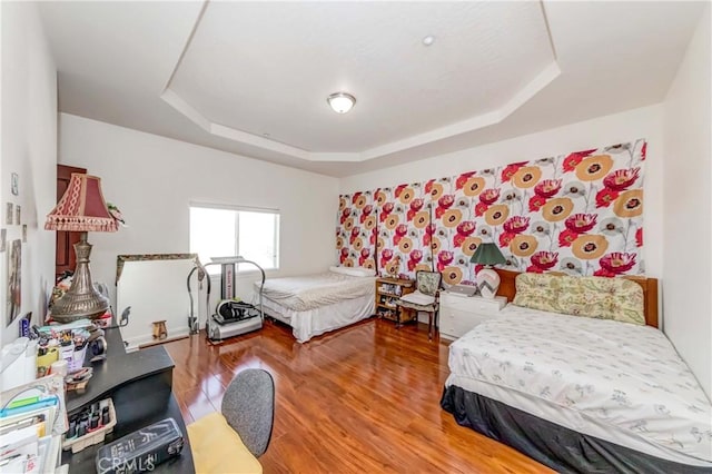 bedroom featuring a raised ceiling and wood finished floors