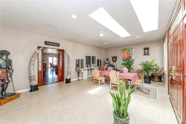 interior space featuring a skylight, light tile floors, and a textured ceiling