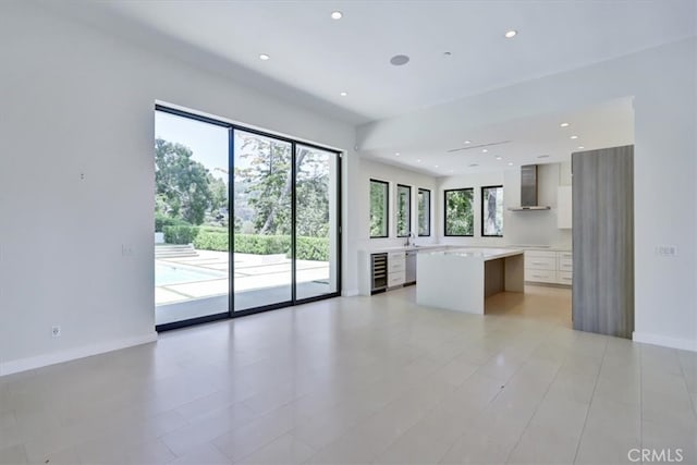 interior space featuring light tile floors, beverage cooler, a kitchen island, and wall chimney exhaust hood