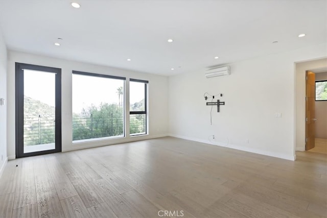 unfurnished room featuring a wall mounted AC and light wood-type flooring