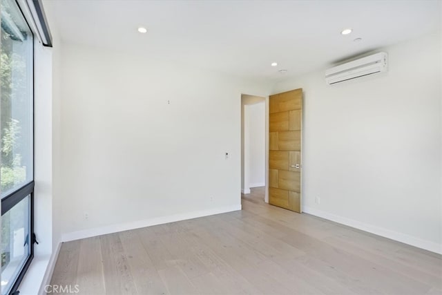 unfurnished room featuring light hardwood / wood-style flooring and a wall unit AC