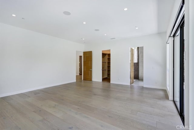 unfurnished bedroom with a walk in closet and light hardwood / wood-style flooring