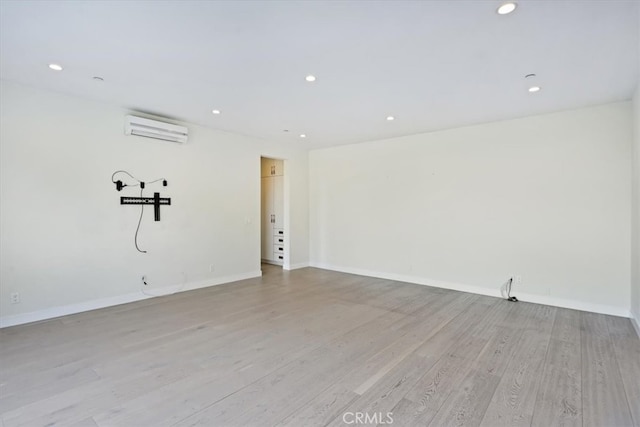 empty room with an AC wall unit and light wood-type flooring