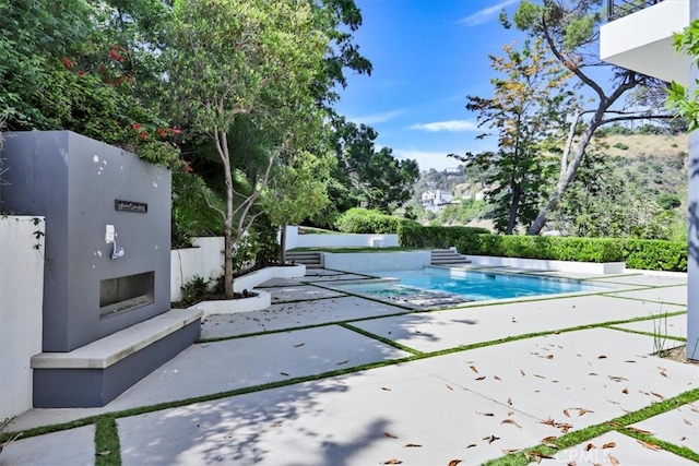 view of pool featuring a patio area and exterior fireplace